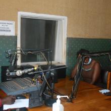 Nakaseke Radio studio, with a presenter at the mixing desk and two people in the studio. 