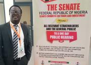 Desmond Oriakhogba next to a poster advertising the Senate hearing.