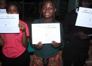 Three young ICT graduates from Kawempe Youth Centre and Community Library show their certificates of achievement.