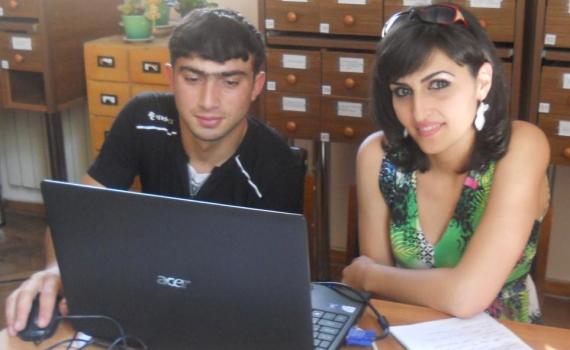 A library trainer shows a young woman trainee how to use a computer to access the internet.