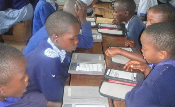 Children in a classroom reading with the e-readers. 