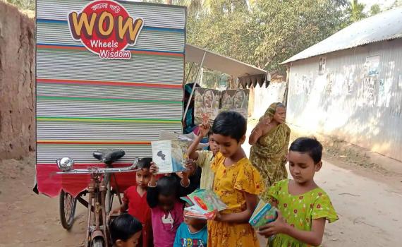 Children collect books from the three-wheeled library, parked in a street in a poor area of Dhaka.